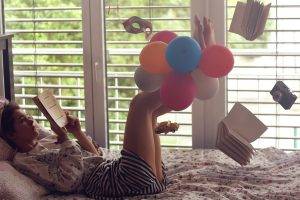 floating reading bed window books balloons women barefoot camera striped clothing venetian masks toys car legs up