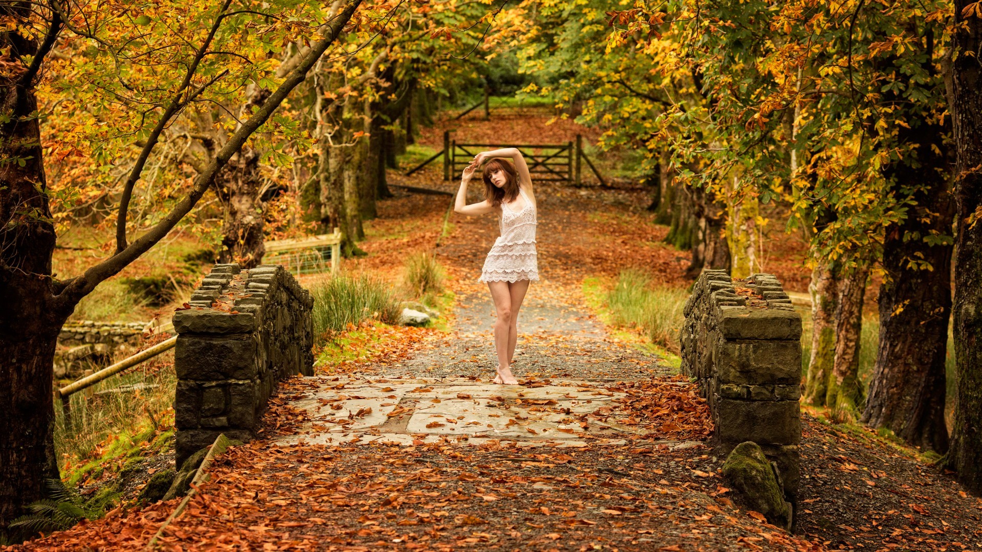 arms up barefoot fall gates women outdoors bridge trees white dress