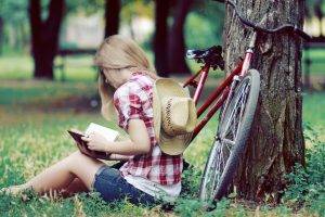 women model blonde women outdoors sitting reading jean shorts shirt cowboy hats bicycle trees park grass