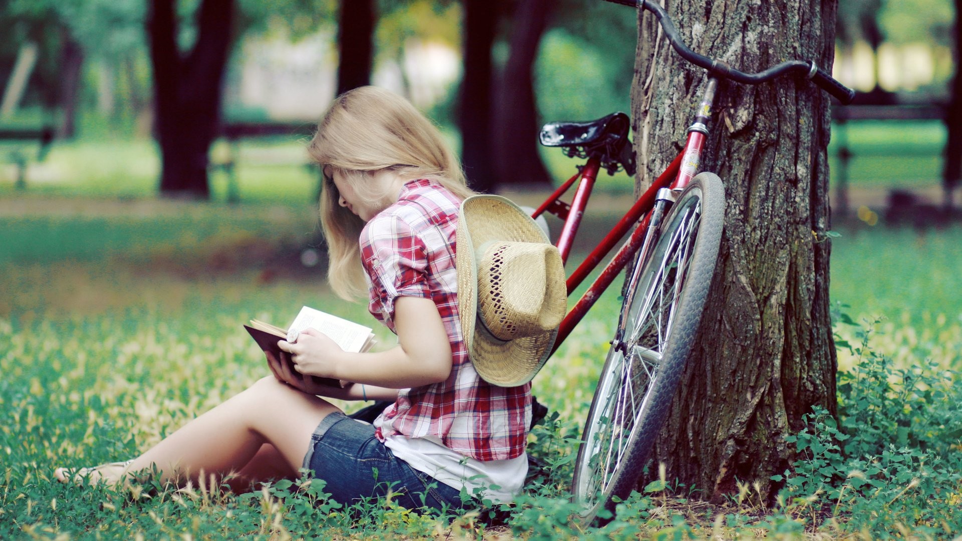 women model blonde women outdoors sitting reading jean shorts shirt cowboy hats bicycle trees park grass Wallpaper
